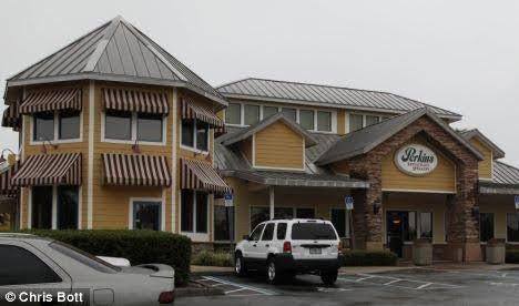 Exterior of Perkins Restaurant with parked cars on a cloudy day.