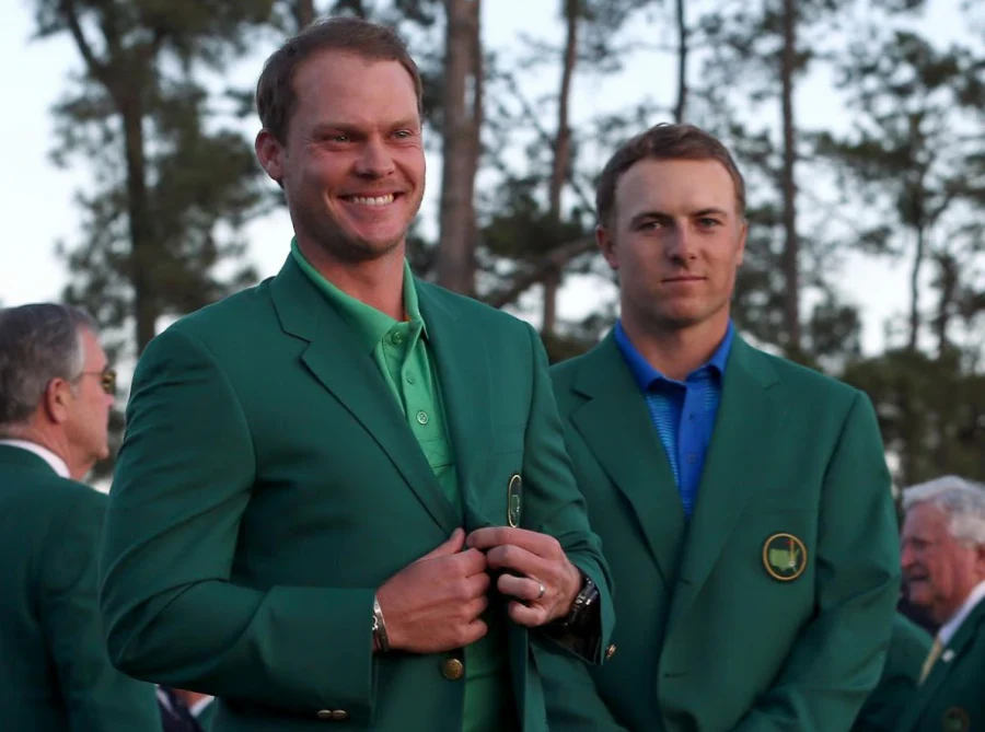 Danny Willett smiling in green jacket as Jordan Spieth stands behind at Masters event.